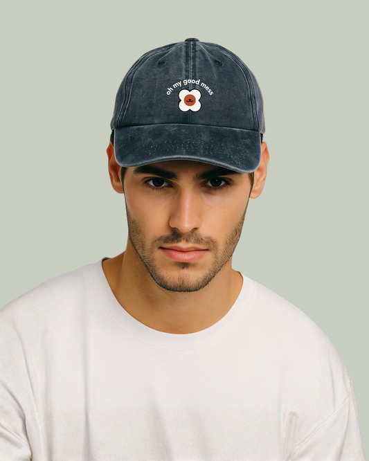 Man wearing an acid wash cap with Good Mess motif logo