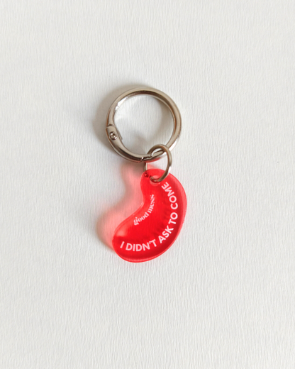 Twinning red acylic bean-shaped pet collar charm with funny text "I didnt ask to come" by Good Mess. For cats and dogs.