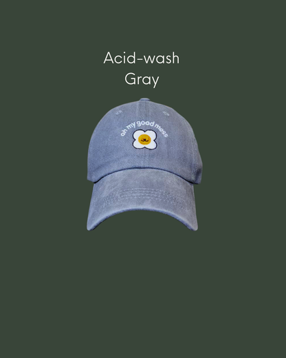Man wearing an acid wash cap in grey gray with Good Mess motif logo